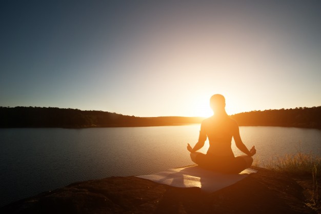 Person der mediterer ved søen ved solnedgang. Mindfulness, afspænding og indre ro i hverdagen.